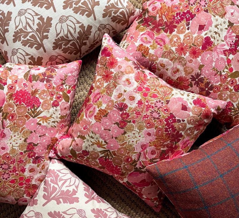 Pile of cushions with bright pink and rust coloured floral textile designs